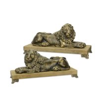 A PAIR OF CAST IRON RECLINING LIONS MOUNTED ON A WOODEN BASE